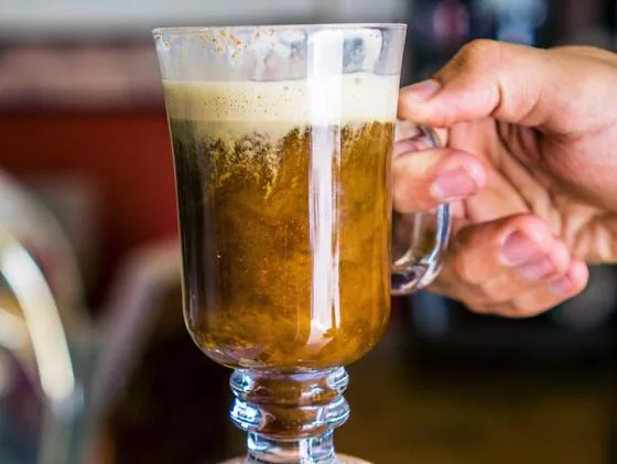Glass of boozy Irish coffee with creamy foam