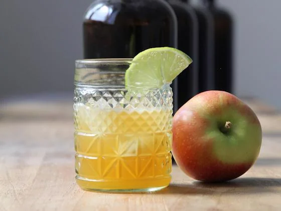Apple cider cocktail with lime garnish and fresh apple