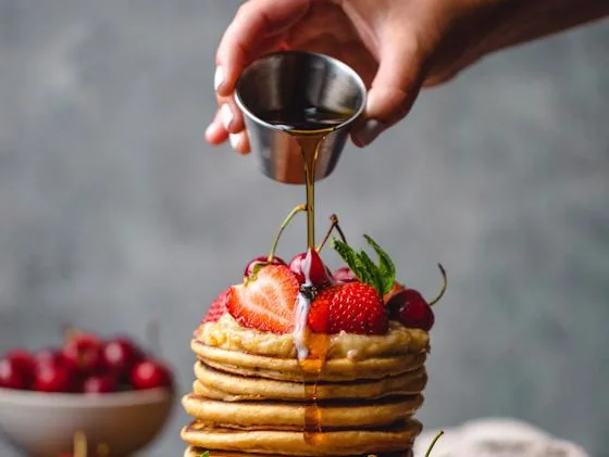 Stack of pancakes topped with strawberries and syrup