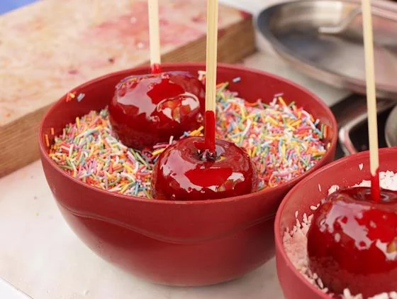Red candy apples covered with colorful sprinkles during a cooking demo