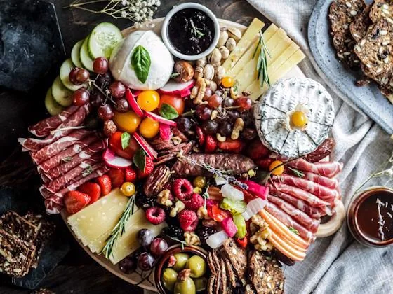 Gourmet charcuterie board with meats, cheeses, fruit, and olives