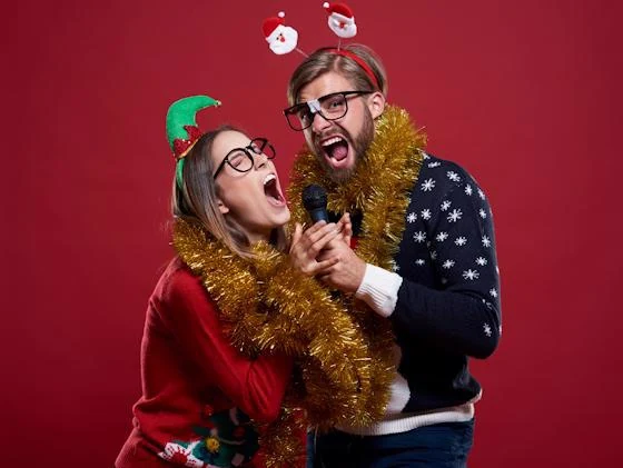 Two friends singing karaoke together during a festive Christmas party