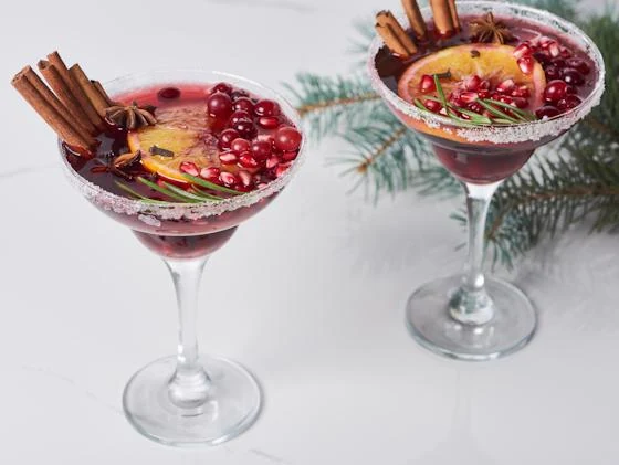 Holiday cranberry cocktails garnished with cinnamon, cranberries, and orange