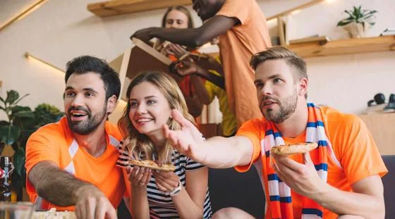 Friends watching March Madness together while enjoying food at a sports viewing party