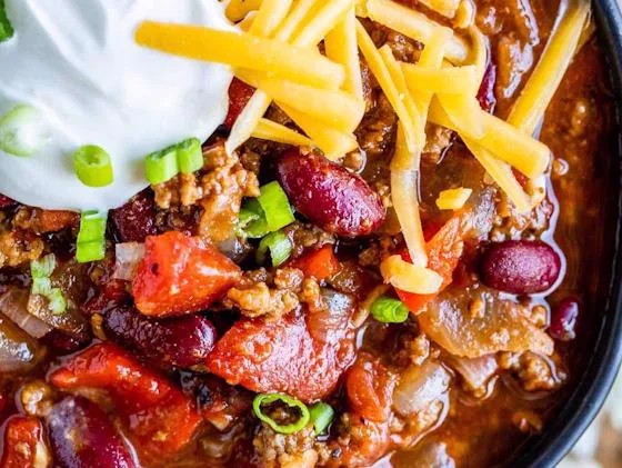 Hearty meat and bean chili topped with cheese, sour cream and green onions