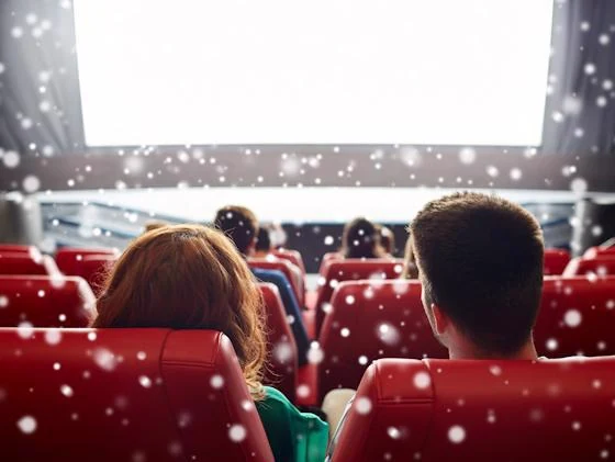 People watching a holiday movie in a theater with falling snow