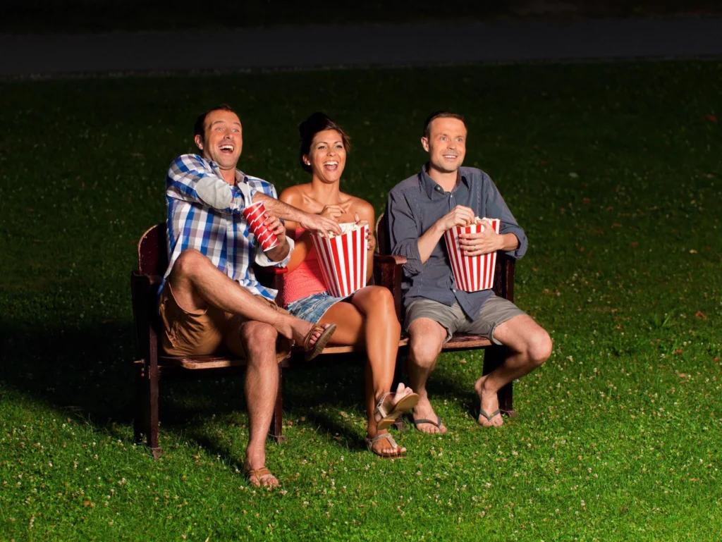 Friends watching an outdoor movie at night with popcorn