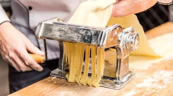 Fresh pasta being cut with a pasta machine