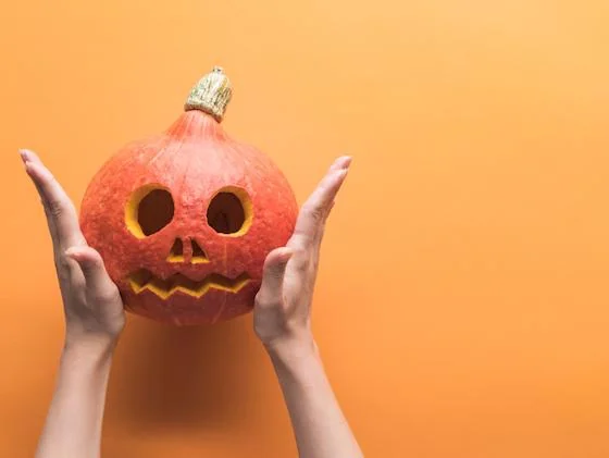 Carved pumpkin held between hands during a Halloween workshop