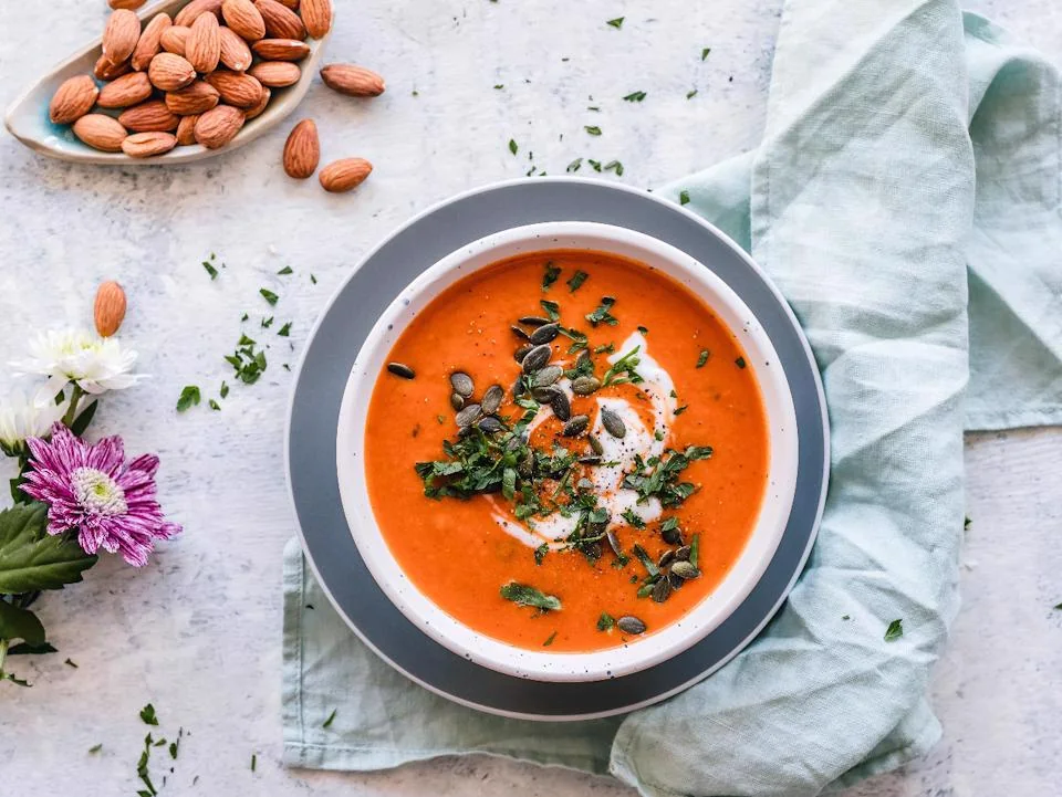 Creamy tomato soup topped with herbs and pumpkin seeds
