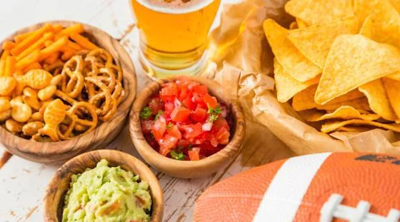 Super Bowl snacks with chips, pretzels, salsa, guacamole, and football