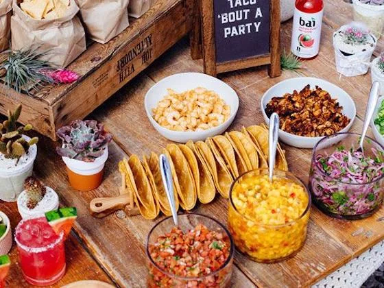 Taco bar with tortillas, fresh toppings, and colorful Mexican-inspired dishes
