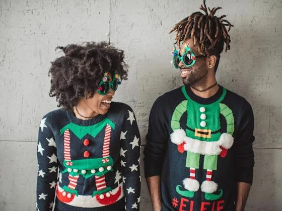 Friends laughing together while wearing festive ugly Christmas sweaters