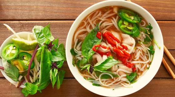 Vietnamese noodle soup with fresh herbs, chili and lime