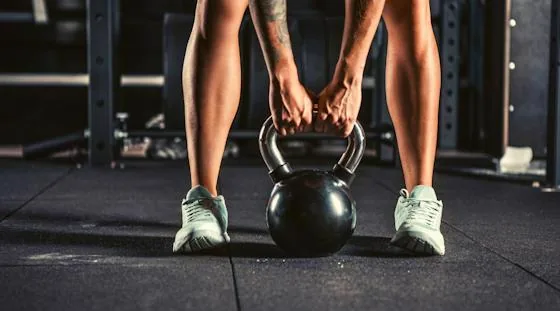 Person lifting a kettlebell as part of a structured workout plan